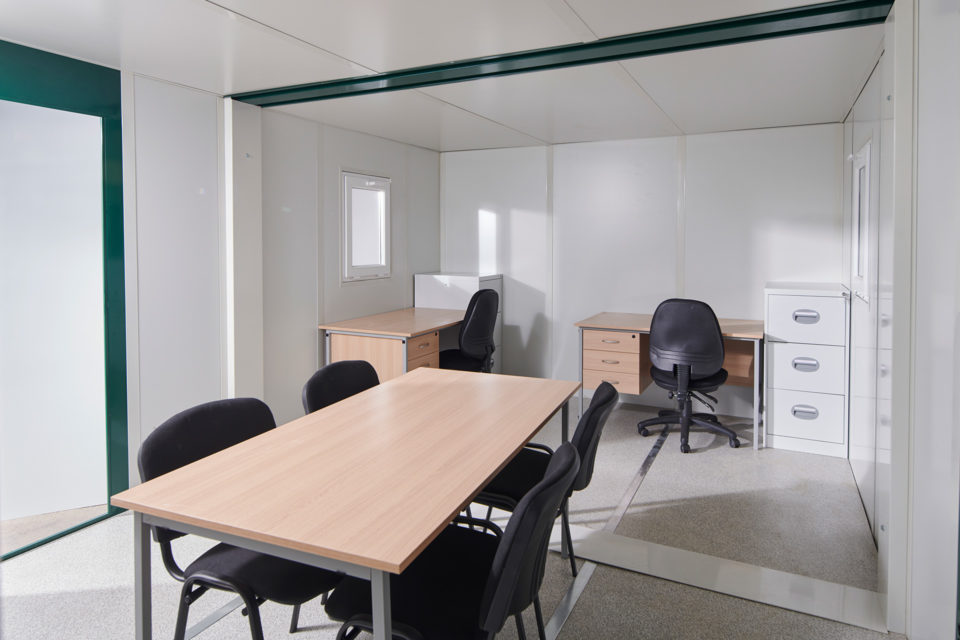 Interior of linked flat pack office with desks and meeting space