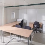 Interior of linked flat pack office cabin with two desks and filing cabinet